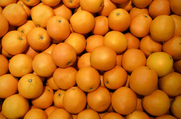 Image of orange fruit on a market stall. A pile of fresh tangerines waiting to be sold in the supermarket. Used for background, fruit wallpaper.
