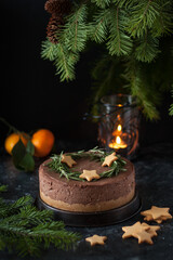 Christmas chocolate cheesecake decorated with rosemary and cookies in the form of stars in warm colors