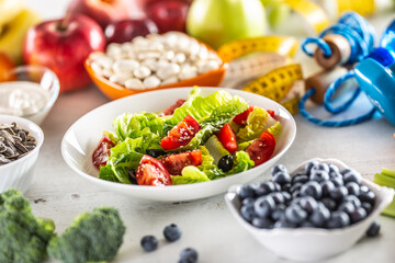 Healthy fresh salad with tomatoes olives and olive oil, surrounded by healthy food and exercise...