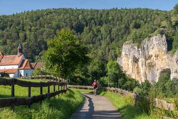 Fototapeta na wymiar beautiful active senior woman cycling with her electric mountain bike in the rocky Upper Danube Valley on the Swabian Alb between Beuron and Sigmaringen