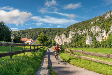 Fototapeta premium beautiful active senior woman cycling with her electric mountain bike in the rocky Upper Danube Valley on the Swabian Alb between Beuron and Sigmaringen