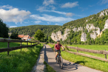 beautiful active senior woman cycling with her electric mountain bike in the rocky Upper Danube...