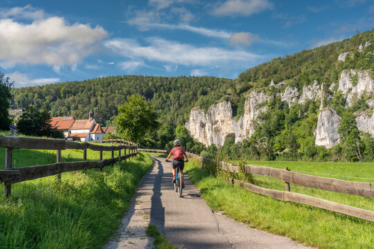 beautiful active senior woman cycling with her electric mountain bike in the rocky Upper Danube Valley on the Swabian Alb between Beuron and Sigmaringen