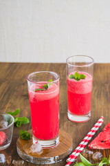 Refreshing soft drink, watermelon lemonade or Aqua fresca in glasses on a brown wooden background. Drink recipes.