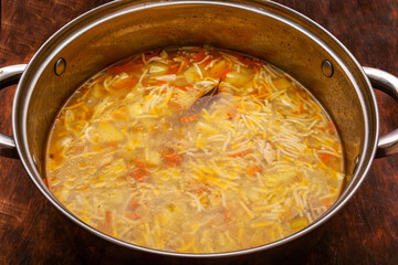 Vegetable soup in a saucepan with pasta and chicken