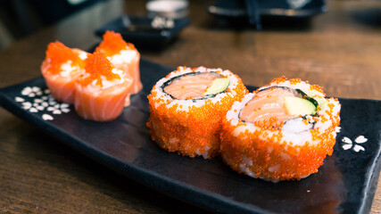 Raw salmon uramaki serve on a sushi plate.