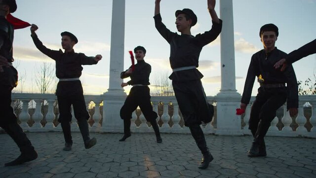 4K Group of Caucasian dancers in local black costumes perform traditional folk dance . Group of Men dancing traditional dance with handkerchief . Outdoor Shot on RED EPIC DRAGON Cinema Camera .