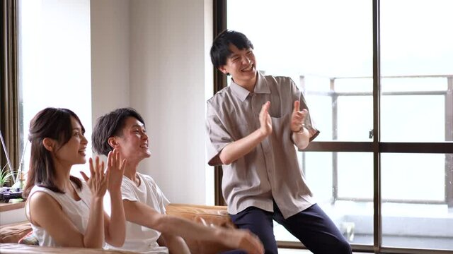 おうちでスポーツを観戦する若い男女