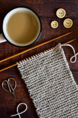 garter stitch knitting project with cup of coffee and wooden buttons 