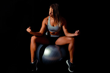 Strong fit woman with dumbbells at black background. Sexy bodybuilder portrait. Low key image.