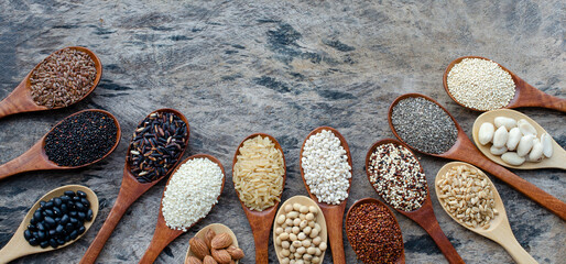 Variety kinds of dry organic cereal and grain seeds in wooden spoon on grunge background, for...