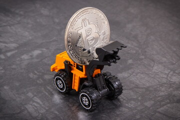 Bitcoin and miniature excavator, symbol of electronic virtual money and mining cryptocurrency