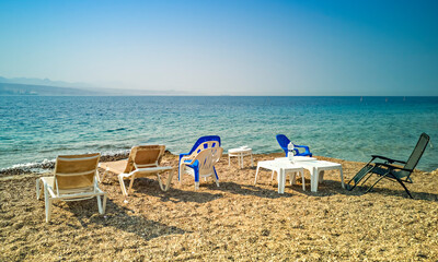 Fototapeta na wymiar Sandy and sunny beach of the Red Sea with chairs and deck-chairs for happy vacation and relaxation after restrictions due to epidemic illness, Red Sea, Middle East
