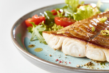 Delicious fried fish fillet with salad leaves and tomatoes