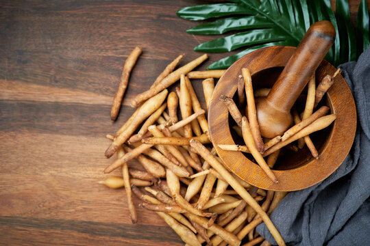 top view fresh finger root or kaempfer (kachai) Thai herb on wooden table and mortar with pestle on the background. copy space. flat lay                                                              