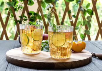 Summer mocktail or iced tea made from peach, lime, and mint. Non-alcoholic cocktail or kombucha drink.