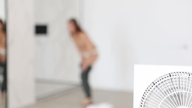 Slim woman takes off her clothes in a studio apartment, out of focus.