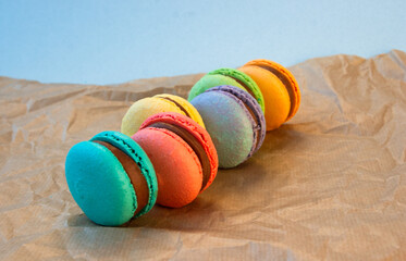 Multicolored macarons with wrapping craft paper on a gray background.