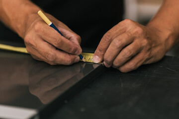 Man marking a surface using a meter in a workshop