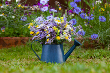 Wild flowers in a blue metal watering can © Ekaterina Shvaygert