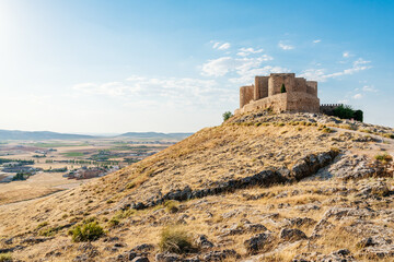 Fortified castle in a hill with fields and village on the horizon