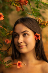 Portrait happy young woman wearing blue dress and standing on Campsis radicans flowers