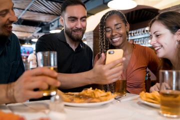 Group of friends using a mobile phone at a restaurant.