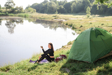Sport girl sit on lake coast and drinking tea