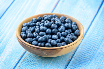 Fresh blueberries in a wooden bowl on an old blue wooden table. Healthy and dietary food concept. Blueberry is an antioxidant
