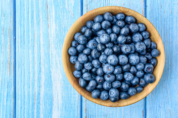 Fresh blueberries in a wooden bowl on an old blue wooden table. Healthy and dietary food concept. Blueberry is an antioxidant. Top View