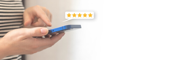 Woman hand pressing on smartphone screen with gold five star rating feedback icon, review the...
