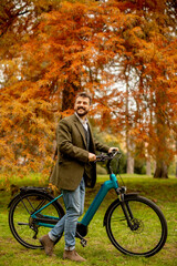 Fototapeta na wymiar Handsome young man with electric bicycle in the autumn park