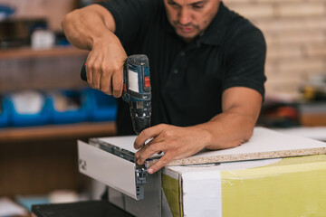 Drill being used by an man to make furniture in a workshop