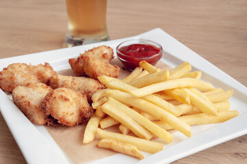 Plate of chicken nuggets with french fries. Sauce of ketchup
