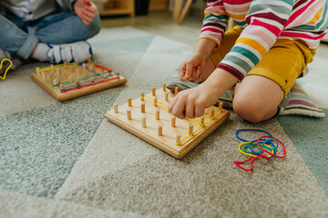 Preschool students playing with geoboard wrapping rubber bands in kindergarten