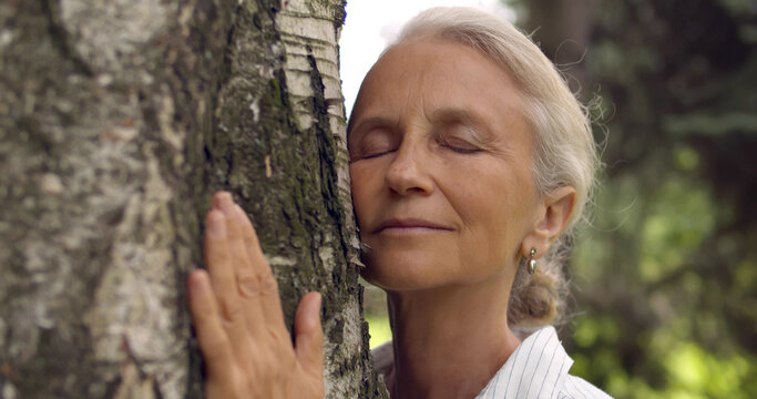 Portrait Of Senior Gray Haired Woman Hugging Tree.