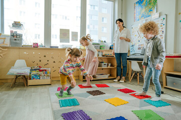 Preschool students having fun time jumping and walking on massage mats