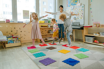 Preschool students having fun time jumping and walking on massage mats