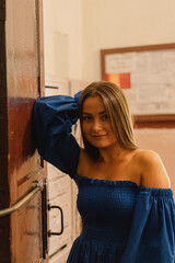 Fototapeta premium Portrait happy young woman wearing blue dress laughing looking at camera standing on street. Urban background