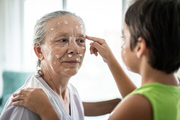 Fototapeta premium Grandmother and little boy putting cream protection on their face