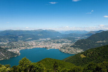 Fototapeta na wymiar Gorgeous view from the hill top at Balcony of Italy, over Lake Lugano, city Lugano and other cities. The view go far into Switzerland, all to the way to the Swiss alps. Shot from the Italian side of t