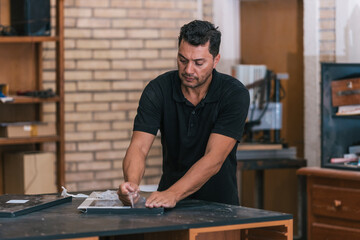 Man removing the protective plastic tape from a piece of furniture