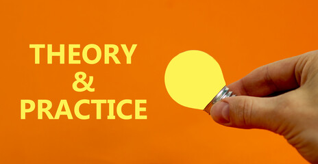 Theory and practice symbol. Businessman holds yellow shining light bulb. Words 'Theory and practice'. Beautiful orange background. Light bulb icon. Business, theory and practice concept. Copy space.