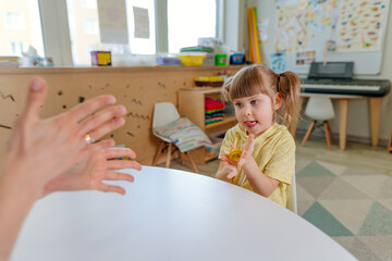 Girl on the lesson of the development of fine motor skills in kindergarten - obrazy, fototapety, plakaty