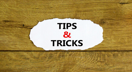 Tips and tricks symbol. Words 'Tips and tricks' on white paper. Beautiful wooden background....