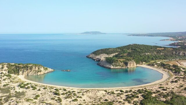 Aerial drone video of semicircular sandy beach and lagoon of Voidokilia, one of the most iconic beaches in Mediterranean sea, with crystal clear turquoise sea, Messinia, Greece