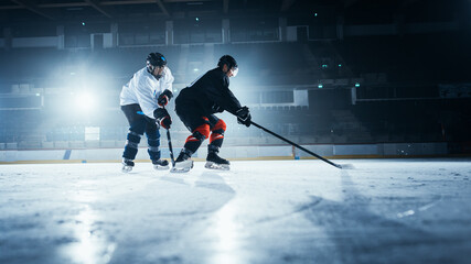 Obraz premium Ice Hockey Rink Arena: Two Young Players Training, Learning Stick and Puck Handling. Athletes Learn how to Dribble, Attack, Defend, Protect, Possesion, Drive the Puck.