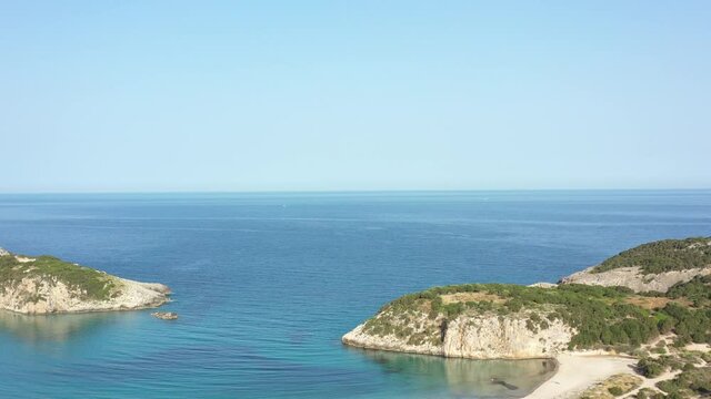 Aerial drone video of semicircular sandy beach and lagoon of Voidokilia, one of the most iconic beaches in Mediterranean sea, with crystal clear turquoise sea, Messinia, Greece