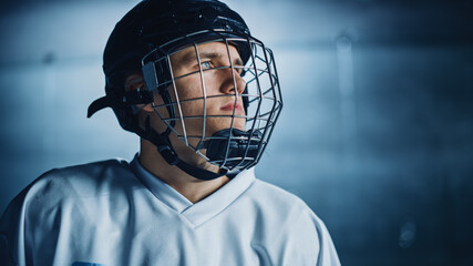 Ice Hockey Rink Arena: Portrait of Confident Professional Player, Wearing Wire Cage Face Mask, Looking afar. Focused Athlete, Determined to Win and be Champion. Portrait Shot