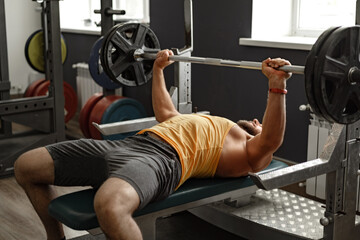 Fototapeta na wymiar Bearded man bodybuilder doing bench press exercise in gym